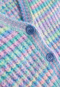 Tissu en maille douce avec des rayures pastel en bleu, vert, rose et violet, présentant deux gros boutons bleus cousus en ligne verticale.