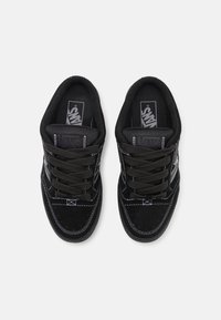Černé tenisky Vans mají svrchní část z broušené kůže, černé tkaničky, bílé prošívání a logo na jazyku. Design je nízký s polstrovaným límcem.