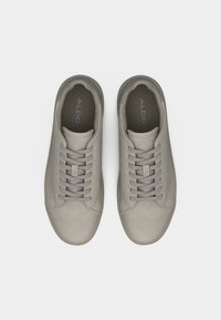 Paire de baskets décontractées lacées de couleur gris clair, avec des bouts arrondis, des coutures visibles et le logo ALDO à l'intérieur des chaussures.