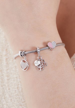 Silberarmband mit einem flexiblen Band, ausgestattet mit Charms: einem pinken und silbernen Herzen, einem perlenverzierten Herzen und einem Familienstammbaum, die unterschiedliche Texturen präsentieren.