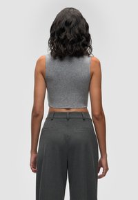 Grå, kort tanktop parret med højtaljede grå bukser. Stofferne ser glatte ud med en blød tekstur. Enkel design uden synlige mønstre.