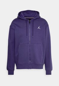Sudadera con capucha morada, con cremallera frontal, bolsillos tipo canguro y un logo blanco. Hecha de una tela suave con puños y dobladillo acanalados.