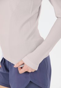 Hellgrau gestreiftes Langarmoberteil mit gerippter Textur und gepunkteten Mesh-Akzenten, kombiniert mit navyblauen Shorts mit abgerundetem Saum für mehr Bewegungsfreiheit.