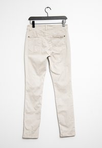 Vaqueros ajustados beige con una textura suave, que cuentan con un bucle en la parte trasera de la cinturilla, dos bolsillos traseros con detalles de costura y un diseño de pierna ajustada.