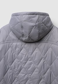 Veste matelassée grise avec capuche, offrant une texture lisse et un motif en losanges. Présente des détails de couture le long des coutures et des bords.