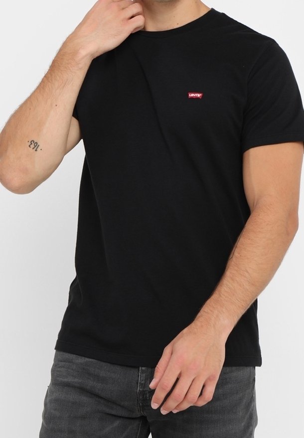 Svart bomullströja med rund halsringning, korta ärmar och en liten röd Levi's-logotyp på bröstet. Bärs med grå jeans.