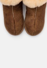 Brown suede ankle boots with a faux fur lining. Rounded toe design, visible stitching, and soft texture at the upper edge.