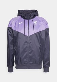 Navy and light purple windbreaker jacket with a hood, featuring a full zipper, side pockets, and a Liverpool FC logo on the chest.
