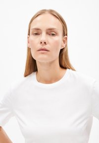 Witte katoenen t-shirt met een ronde hals en korte mouwen. Eenvoudig ontwerp, gladde textuur, weergegeven tegen een effen achtergrond.