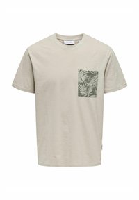 T-shirt a maniche corte beige chiaro con una tasca quadrata e un motivo di foglie tropicali verdi. Realizzato in materiale morbido e confortevole.