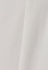 Pehmeä, teksturoitu kangas off-white-värissä, jossa on sileä pinta ja hienoinen kiilto, sisältäen hienovaraisia sävyvaihteluita ja valon heijastuksia.
