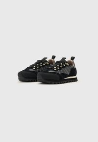 Adidași negri din materiale de ace suede și piele, cu ochiuri aurii, dungi albe, o talpă texturată și un tab pentru prindere la călcâie.