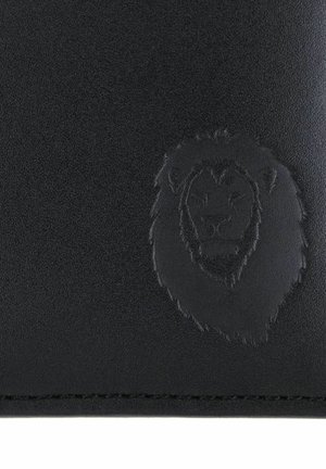 Surface en cuir noir avec emblème en relief de tête de lion près du bord cousu.