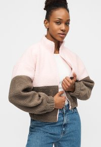 Ροζ και καφέ φλις μπουφάν με μπλοκ χρωμάτων, ψηλό γιακά, φερμουάρ εμπρός και φαρδιά μανίκια. Υφή υφάσματος, χαλαρή εφαρμογή.