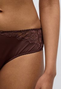 Καφέ δαντελένια εσώρουχα με φλοράλ δαντελένιο τελείωμα κατά μήκος της μέσης, με απαλό, ελαφρώς γυαλιστερό ύφασμα και κλασικό κομψό σχέδιο.