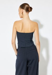 Mono de rayas marino con un diseño sin tirantes, que cuenta con un torso ajustado y pantalones de pierna ancha, confeccionado en una tela suave.