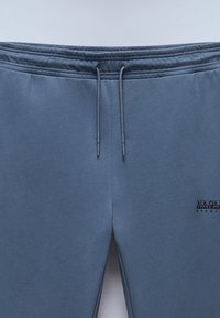Gray jogger pants made of soft fabric, featuring an elastic waistband with drawstrings and a small logo on the left side.