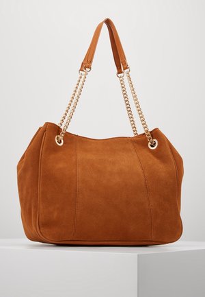 Sac à main en daim marron avec doubles sangles chaîne dorée et repose-épaules en cuir, présenté sur un piédestal blanc sur fond uni.