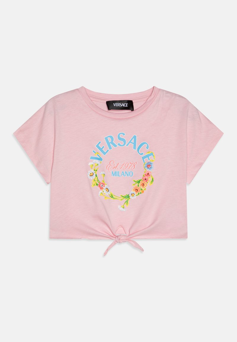 Rožinė medvilninė trumpa marškinėliai su gėlių vainiko dizainu ir užrašu "VERSACE Est. 1978 MILANO". Kaklo apdaila surišta mazgu prie apačios.
