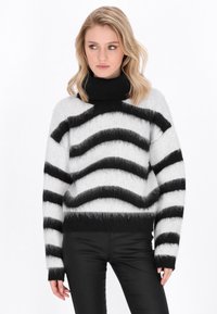 Zwart-wit gestreepte trui met een hoge, zwarte col en een fuzzy textuur; brede, golvende strepen over het lichaam en de mouwen.