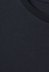 Lähikuva tummansinisen kankaan hienosti ribbikuviollisesta pyöreästä pääntiestä, joka näyttää tekstuurin ja ompelusaumat.