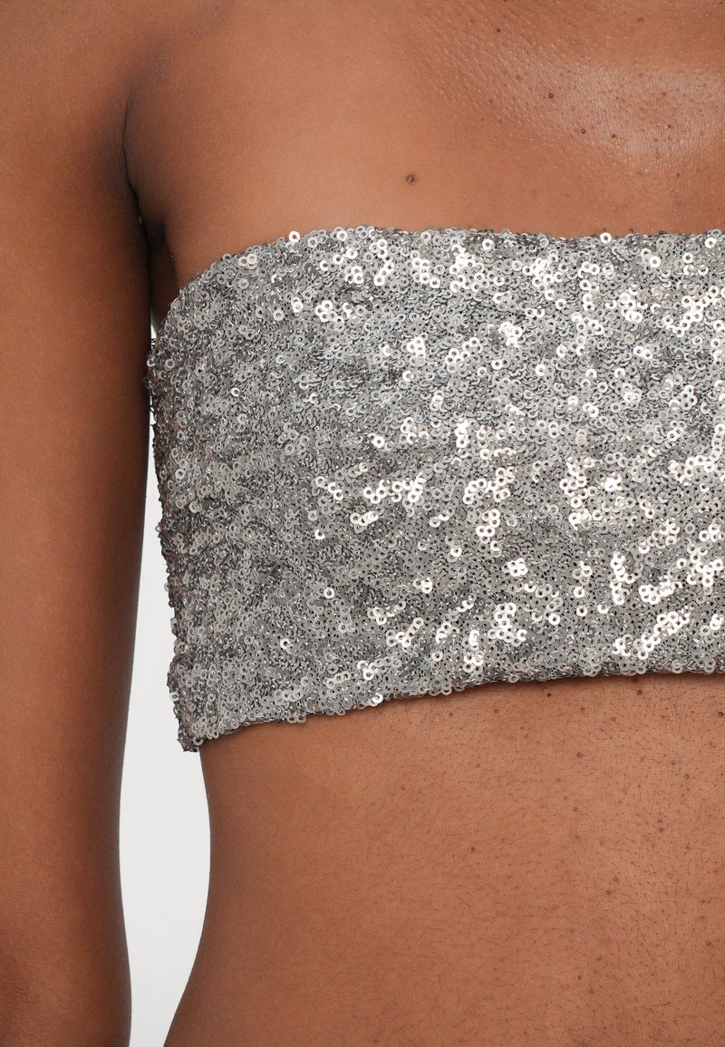 Silverfärgad paljettbandeau med en strukturerad yta, som har en tajt passform och elastisk midja, designad för att täcka överkroppen utan axelband.