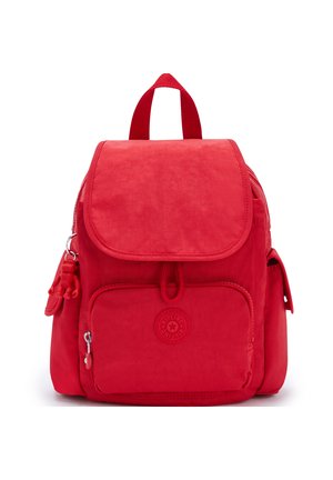 Red nylon backpack with a flap closure, front zip pocket, and side pockets. Features a textured finish and a small monkey keychain attachment.