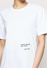Hvid bomulds t-shirt med korte ærmer og rund halsudskæring, med sort tekst: "LUKKET FOR EVIGT OG EVIGT... OG EVIGT."
