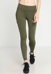 Oliwkowe legginsy o dopasowanym kroju, z kropkowanymi akcentami po bokach i wysokim pasem. Wykonane z elastycznego materiału.