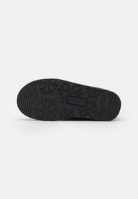 Black rubber shoe sole featuring a textured surface with snowflake patterns and horizontal grooves for traction.