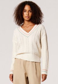 Cremfarbener Kabelstrickpullover mit V-Ausschnitt, der pastellfarbene, gestreifte Akzente am Kragen und an den Bündchen sowie einen gerippten Saum aufweist.