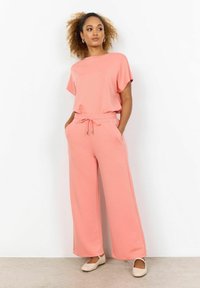 Lichtroze loungewear set met een shirt met korte mouwen en brede broekspijpen. De stof is zacht met een elastische tailleband en een trekkoord.