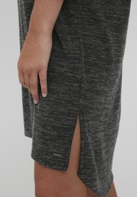 Pelēka adīta kleita ar sānu šķēlēm un birku, uz kuras redzams zīmola nosaukums. Materiāls ir ar teksturētu, melnbaltu modeli. Kleita ir brīvi pieguļoša.