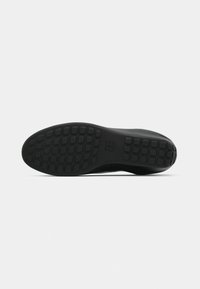 Black rubber shoe sole featuring a textured surface with rectangular and square patterns for traction. Smooth edges with no visible branding.