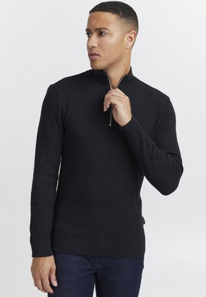 Pulover negru cu fermoar, cu un model texturat de tricot, cu manșete și tiv din material strâns. Are un guler cu jumătate de fermoar și un design slim fit.