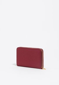 Cartera burdeos con cremallera hecha de cuero suave con accesorios en tono dorado; forma rectangular, diseño minimalista y superficie texturizada.