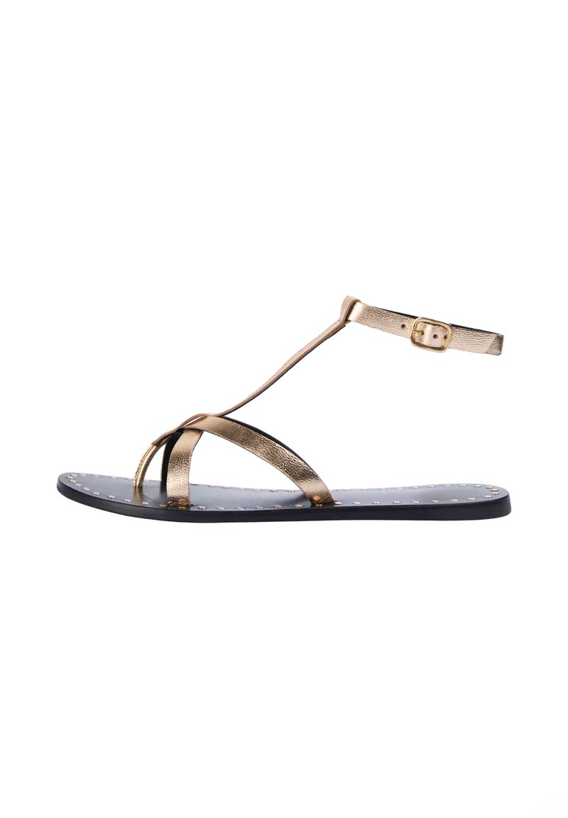 Gold metallic sandal with thin straps, a toe loop, and ankle buckle. Black sole features small gold studs for texture and detail.