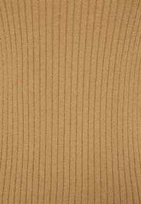 Gros plan d'un tissu côtelé beige avec des rayures verticales en relief et une surface douce et texturée.