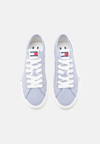 Ανοιχτό μπλε καμβά παπούτσια με λευκά κορδόνια, λευκές λαστιχένιες σόλες και λογότυπο Tommy Jeans στη γλώσσα και στο πλάι.