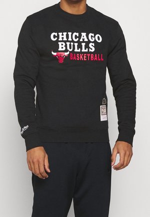 Sweatshirt noir arborant le texte "CHICAGO BULLS" et "BASKETBALL" en blanc et rouge. Poignets et ourlet côtelés, avec une étiquette de logo sur le côté.