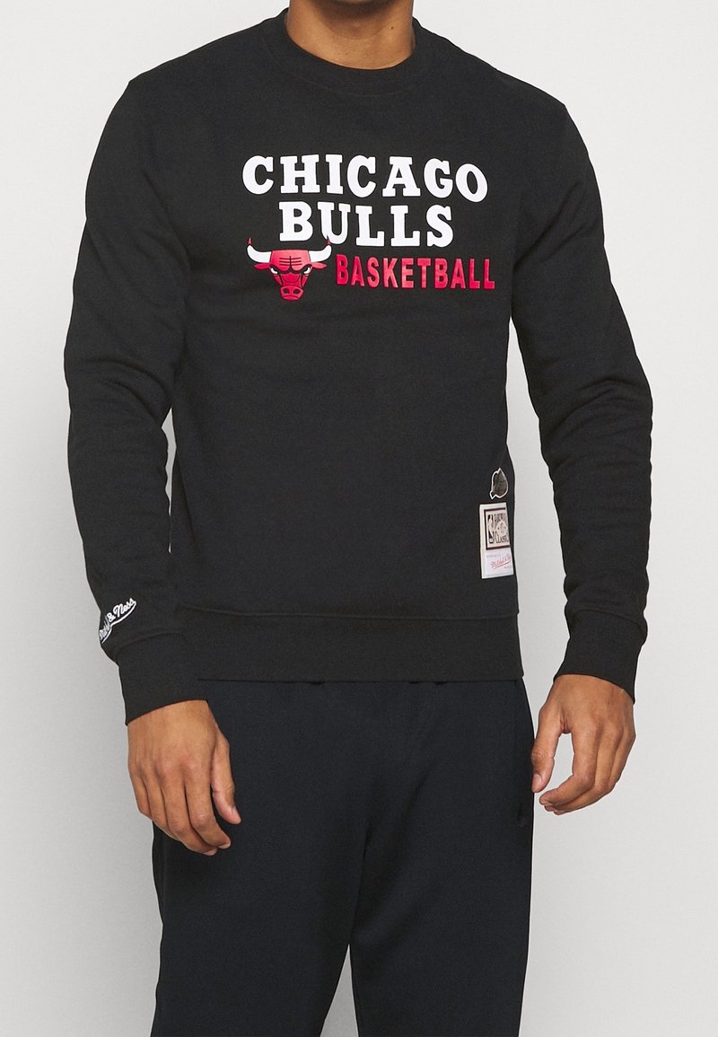 Svart sweatshirt med texten "CHICAGO BULLS" och "BASKETBALL" i vitt och rött. Ribbad muddar och fåll, med en logotag på sidan.