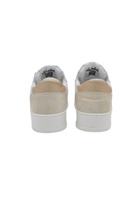 Zapatillas blancas con acentos de ante beige en el talón, parte superior de cuero suave, suelas de goma y diseño de punta redonda.