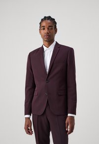 Burgundy színű, slim fit szabású, egygombos zakó, hegyes hajtókával, két gombos záródással és klasszikus galléros fehér inggel.