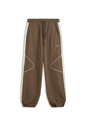 Brązowe spodnie dresowe z elastycznym paskiem w talii i mankietami, białe paski boczne, skośne białe lamówki na nogawkach oraz przednie kieszenie.