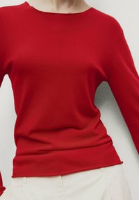 Pull rouge à manches longues avec un col rond et une texture douce, présentant une silhouette ajustée et une finition lisse sans coutures.