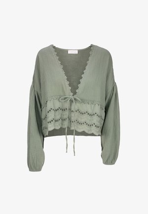 Hellgrüne, langärmelige, gekürzte Bluse mit V-Ausschnitt, Spitzenbesatz und einer Schleife in der Taille. Der strukturierte Stoff hat ein gewelltes Muster.