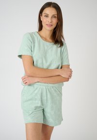 Mintgroen loungewear-set gemaakt van een textuurstof met een bloemenpatroon. T-shirt met korte mouwen en shorts met een elastische taille. Ontspannen pasvorm.