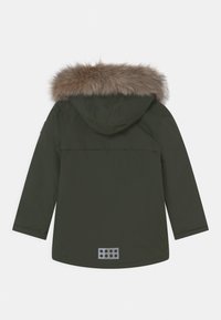 Olivově zelená parka s kapucí podšitou kožešinou, dlouhými rukávy a šedou obdélníkovou nálepkou s otvory na zadní straně. Hladká textilie.