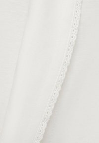 Material alb cu o textură netedă, având o dantelă delicată la margine. Dantela are mici modele decupate.