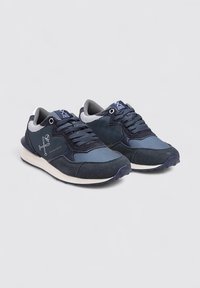 Zapatillas de navy con una mezcla de tela lisa y texturizada, que presentan un cordón destacado, una lengüeta acolchada y acentos de suela blanca en contraste.